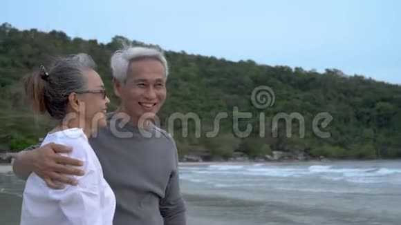 亚洲夫妇年长的老人退休后在日落海滩度蜜月的家庭里休息拥抱视频的预览图