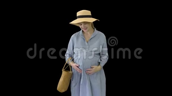 美丽的孕妇穿着夏装戴着帽子摸着她的肚子阿尔法频道视频的预览图