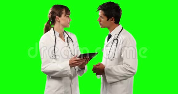 医生的侧视讨论和持有一个绿色屏幕的数字平板电脑视频的预览图