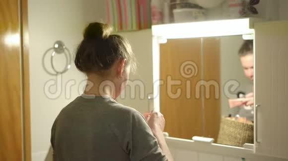 年轻女子在浴室里看着装有化妆品的盒子视频的预览图
