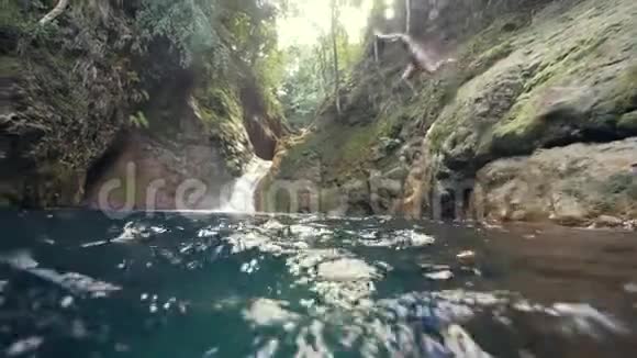 一位正在度假的年轻女子跳下瀑布在水下游泳视频的预览图