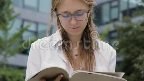 一个年轻的金发女人在公园里拿着杂志视频的预览图