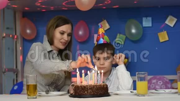 妈妈带着孩子在生日蛋糕上点蜡烛视频的预览图
