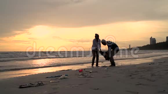 亚洲夫妇退休老人在日落海滩家捡垃圾视频的预览图