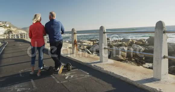 一对老夫妇走在海边的电子滑板车旁边视频的预览图