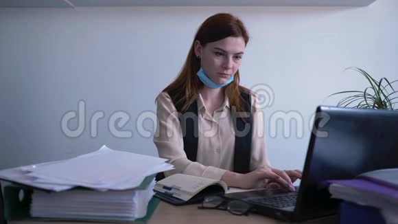 病毒传播一名戴着医用口罩的不健康妇女在办公室的电脑上工作一名生病的女商业雇员视频的预览图