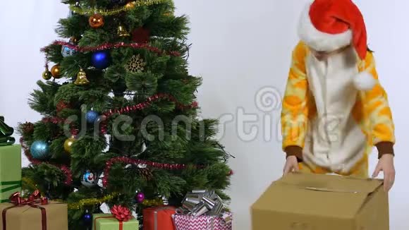 女孩拖着盒子坐在圣诞树旁视频的预览图