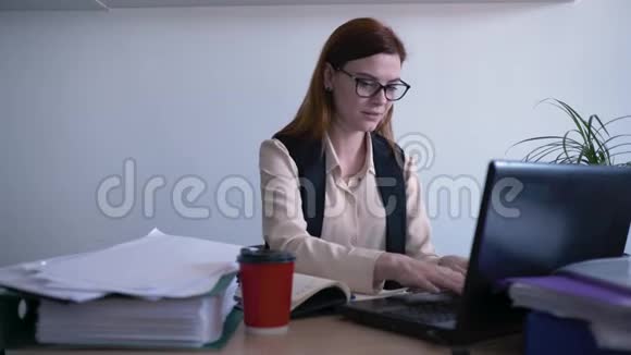 办公室工作人员戴眼镜的妇女商务工作人员一边喝咖啡一边看屏幕视频的预览图