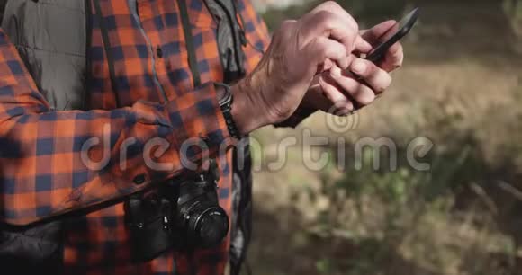 近距离观看森林中持有智能手机的老人视频的预览图