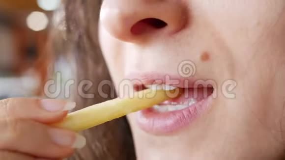 不可辨认的年轻女子正在快餐店吃炸薯条她手里拿着一只手土豆嘴特写视频的预览图