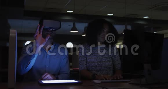 年轻的办公室管理人员正在研究数码平板电脑并在现代办公室使用VR头盔视频的预览图