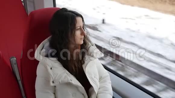 冬天年轻女子坐现代高速列车向窗外张望视频的预览图