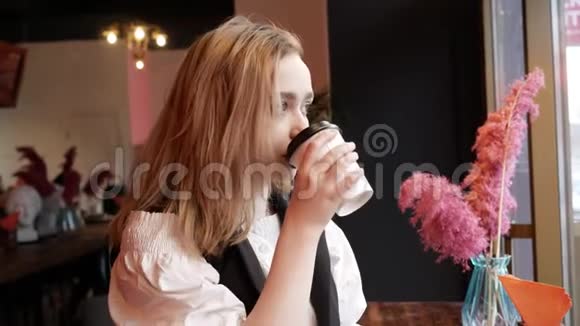 咖啡馆里的金发女郎从纸杯里喝咖啡望着窗外视频的预览图