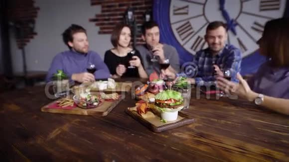 餐厅的木桌上有很多素食小吃背景中有一群朋友是视频的预览图