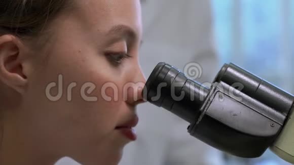 放大医学研究科学家在实验室显微镜下观察的侧视视频视频的预览图