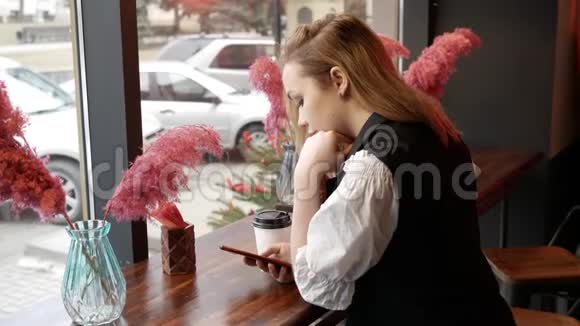 在咖啡馆喝咖啡看电话的年轻女子视频的预览图