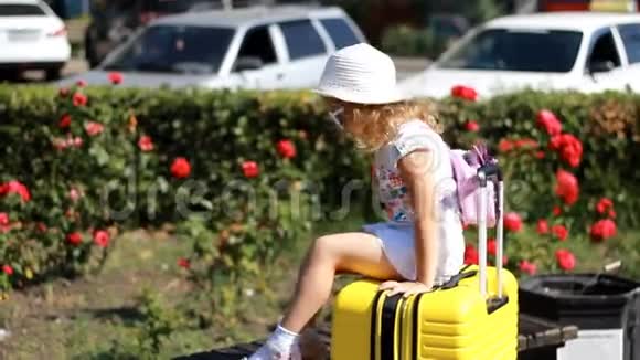 孩子等着旅行小女孩游客坐在一个大黄色的手提箱上行李视频的预览图