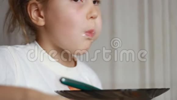 孩子用勺子汤吃饭午餐结束一个小女孩坐在家里做饭和吃饭的桌子上的肖像视频的预览图