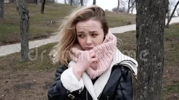 美丽的金发女郎冻死在公园散步生病了她咳嗽视频的预览图
