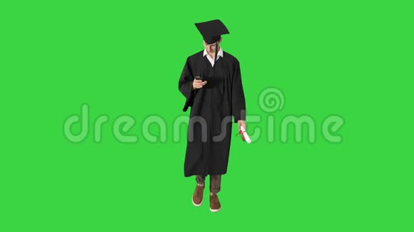 年轻的研究生在绿色屏幕上行走时使用手机Chroma键视频的预览图