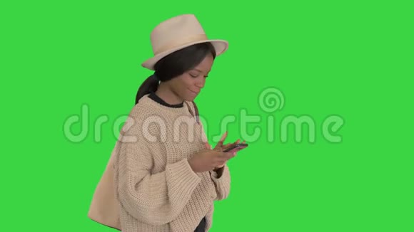戴着帽子的非裔美国女人手机上的短信在绿色屏幕上微笑Chroma键视频的预览图