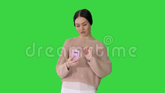 随意的黑发女孩微笑着在手机上自拍的绿色屏幕Chroma键视频的预览图