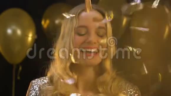 微笑的金发女人拿着香槟酒杯站在掉落的纸屑下派对视频的预览图