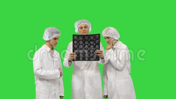 三位医生有节奏地看着一个病人在绿色屏幕上的x光照片Chroma键视频的预览图