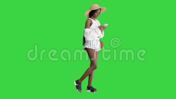 迷人的年轻非洲妇女穿着夏季服装使用手机在绿色屏幕Chroma键视频的预览图