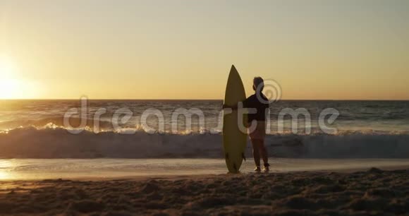 海滩上带冲浪板的老女人后景视频的预览图