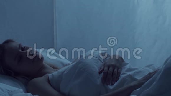 年轻女子晚上躺在床上患有失眠症美丽的金发女郎暮光之城视频的预览图