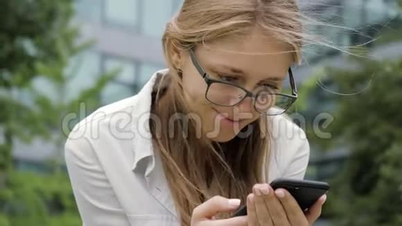年轻微笑的女人在户外用电话视频的预览图