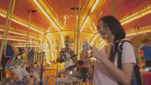 旋转木马骑马在游乐园背景与快乐美女亚洲女人看门票和看相机人民视频的预览图