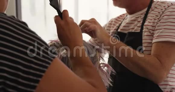 近距离观看的女人她的头发由两个理发师设计视频的预览图