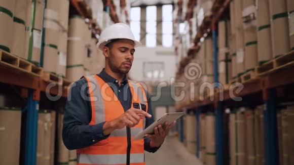 整理现代非洲裔美国人仓库工人的肖像使用数字平板电脑仰望高大的货架视频的预览图