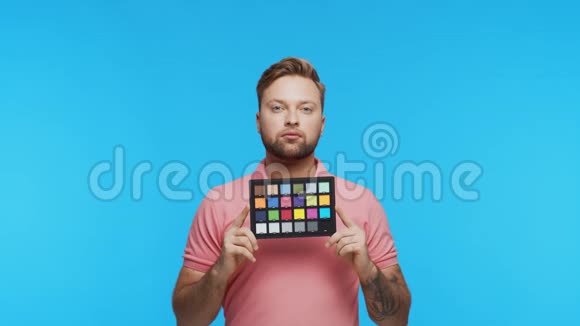 充满活力的背景下表现出来的年轻人画室肖像的英俊的人拿着彩色支票色彩和色彩视频的预览图