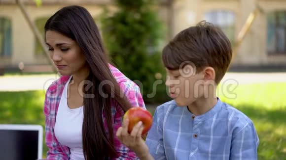 母亲对儿子坐在公园里吃苹果表示悲伤视频的预览图