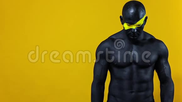 男性健美运动员脸上有黄色的艺术和黑色的身体油漆有健美感的人的彩色肖像视频的预览图
