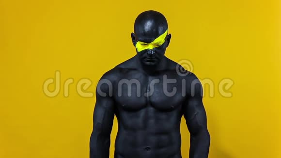 男性健美运动员脸上有黄色的艺术和黑色的身体油漆有健美感的人的彩色肖像视频的预览图