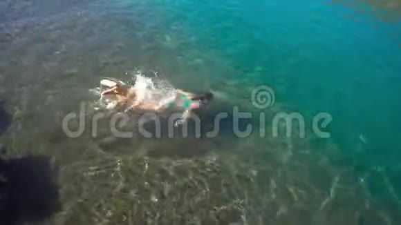 年轻女子跳进水里在海洋上休息视频的预览图