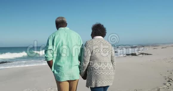 在海滩边散步的老夫妇的后景视频的预览图