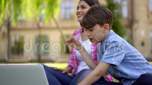 带孩子的妈妈在户外使用笔记本电脑上课视频的预览图