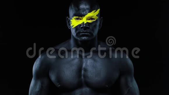男子体育迷和健美运动员与黄色的脸艺术和黑色的身体油漆他的彩色画像视频的预览图
