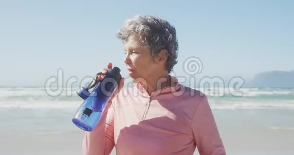高级妇女在海滩上喝水视频的预览图