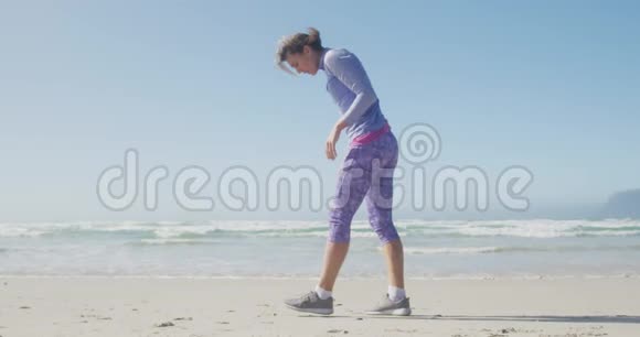 运动的女人在沙滩上系鞋带视频的预览图