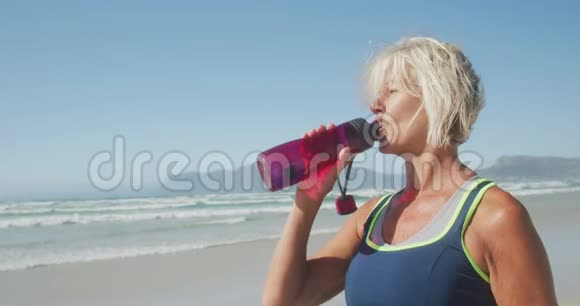 运动妇女在海滩上饮水视频的预览图