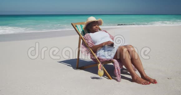 在海滩边看到一位使用笔记本电脑的老妇人视频的预览图