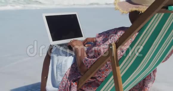 海滩上使用笔记本电脑的老妇人的后景视频的预览图