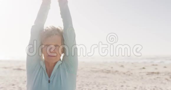在海滩上做瑜伽的高级女性视频的预览图
