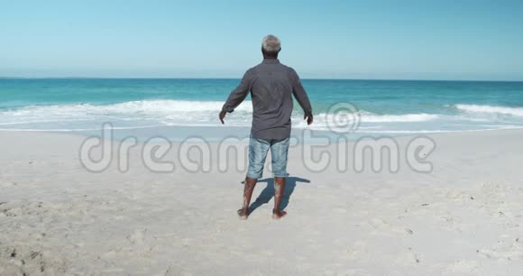 后景老人在海滩上举起双臂视频的预览图